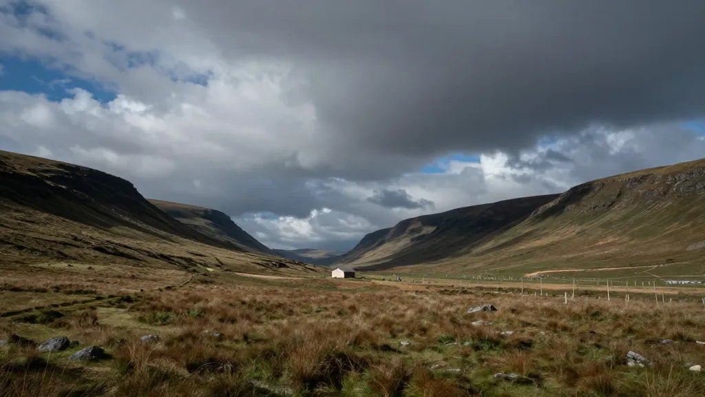Wide valley with a single house in distance under dramatic sky