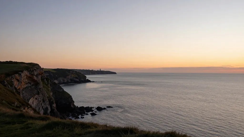 Distant coastal cliff overlooking sea at sunset, UK housing skyline visible far away