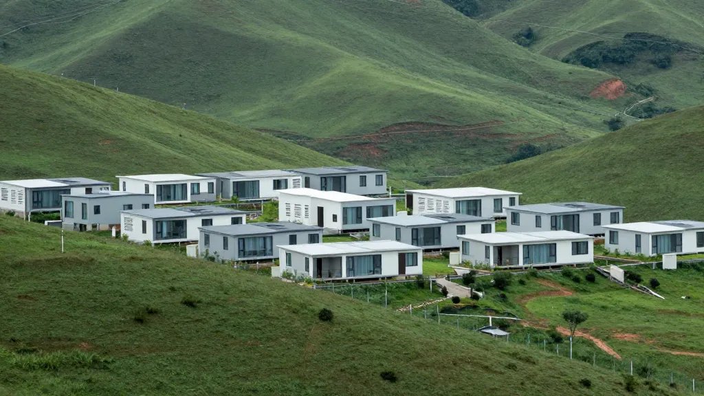 Distant view of a modular housing village on a green hillside