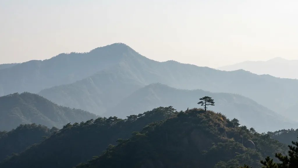 Expansive mountain range, solitary pine on ridge, soft mist