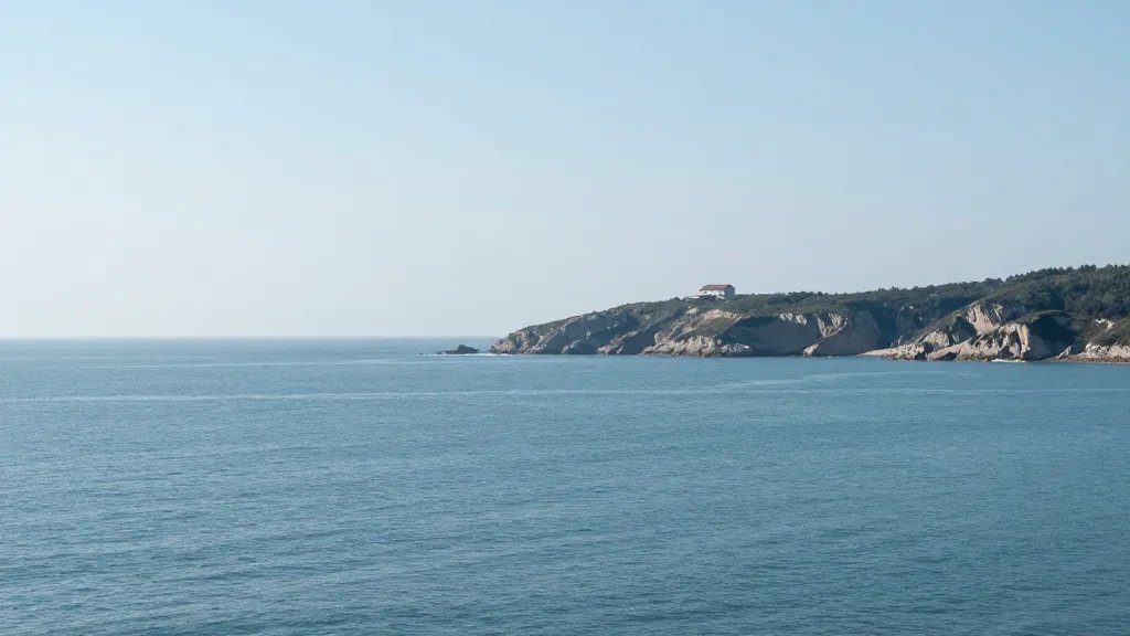 Expansive coastline with a single distant property perched on cliffs