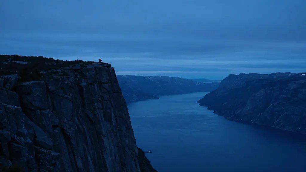 Distant fjord cliffscape at blue hour, single rock outcrop silhouette