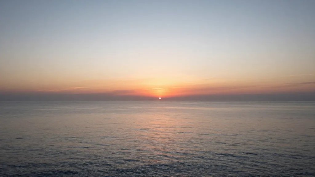 Expansive coastline at sunset with calm sea and distant horizon