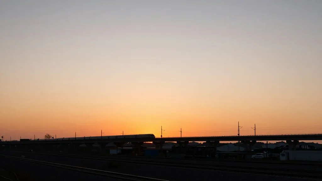 Expansive railway town horizon with new transport link silhouette, sunset