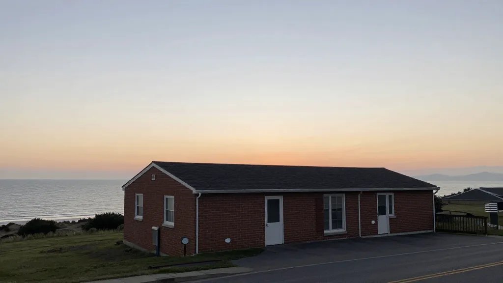 Expansive coastline view behind a standalone brick rental building at dawn