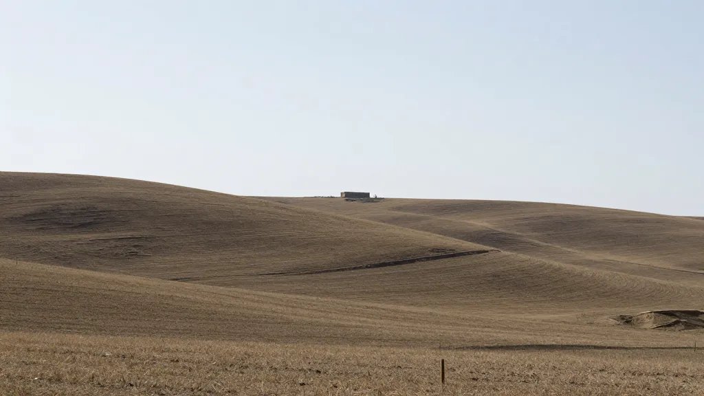 Distant landscape showing a rural hillside with a single, discreet new structure in the distance