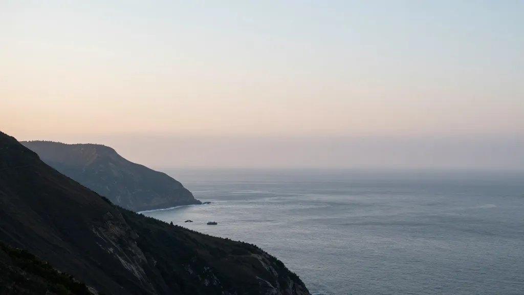 Expansive coastal cliff with distant horizon, misty morning light