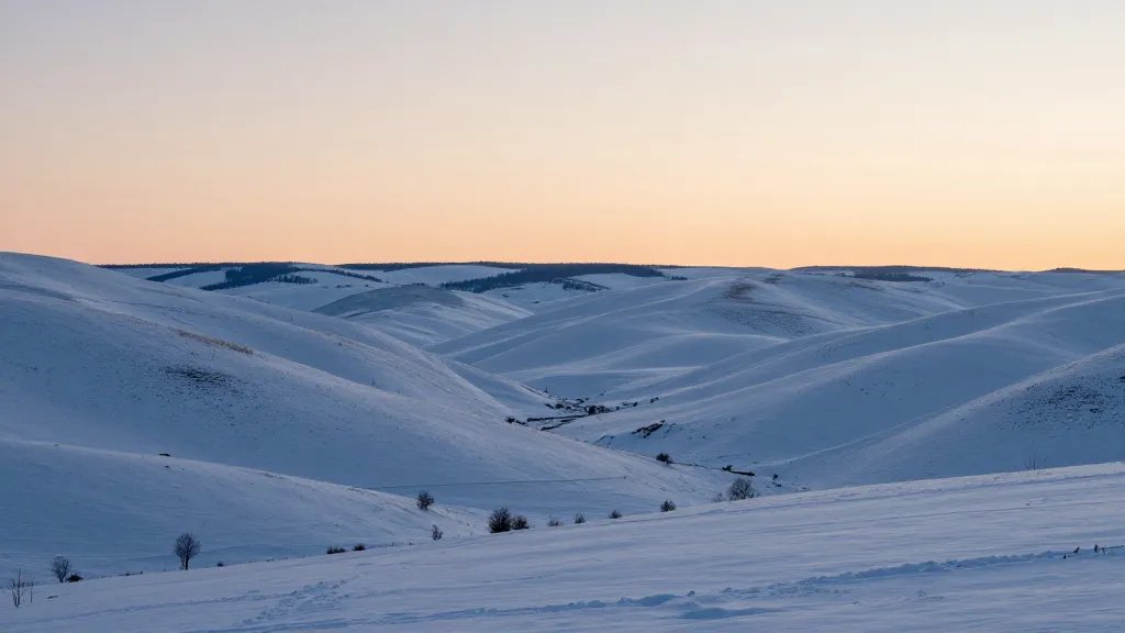 Distant landscape of a quiet, snow-blanketed valley at sunrise