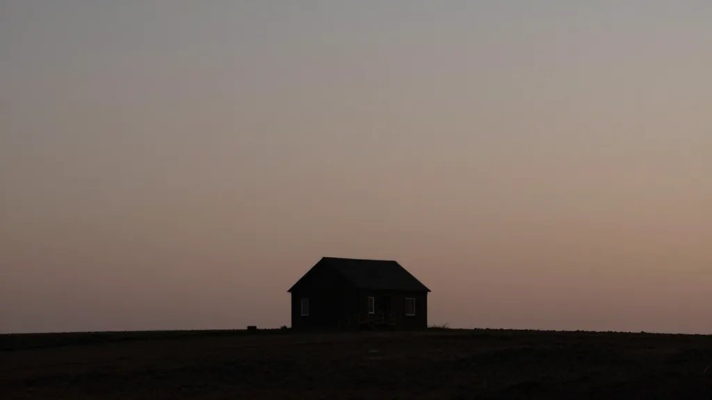 Distant view: a single sturdy house silhouette against dusky sky