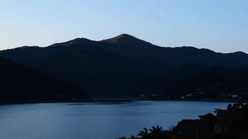 Mountain ridge silhouette, clear sky over serene valley lake