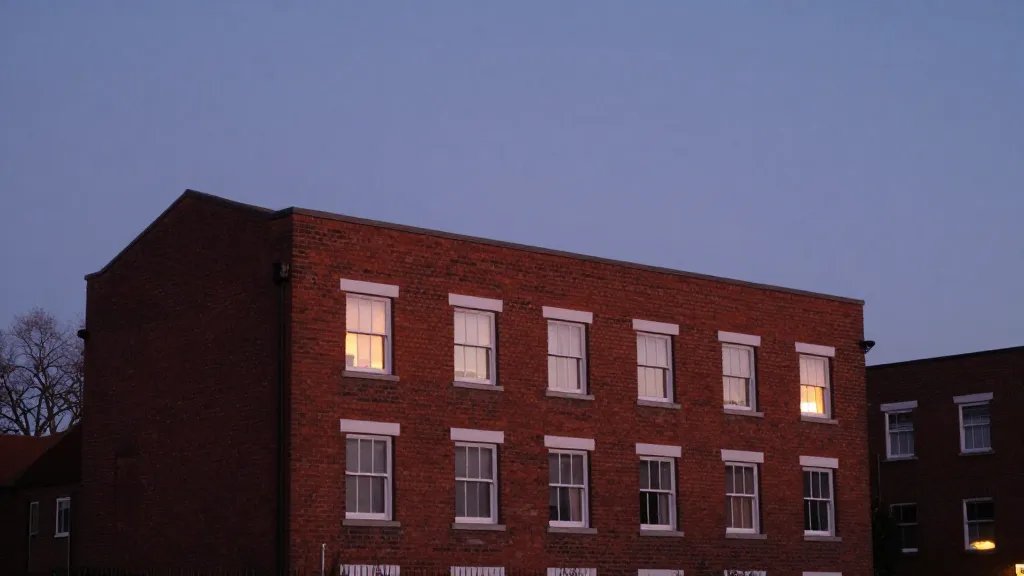 Distant view of a red-brick council house at twilight, single dwelling, soft urban glow