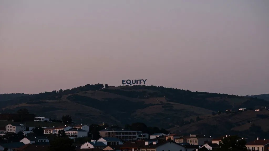 Distant hillside village at dusk, single modern equity loan signage on distant roofline