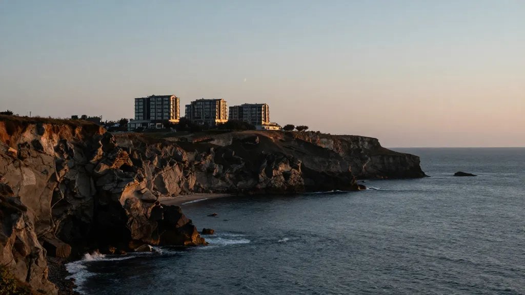Expansive coastline cliffs, lone contemporary housing development silhouetted on horizon