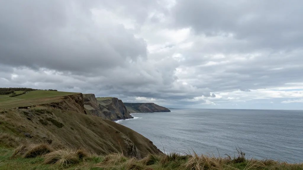 Expansive coastal cliffs under a dramatic cloudy sky, distant view