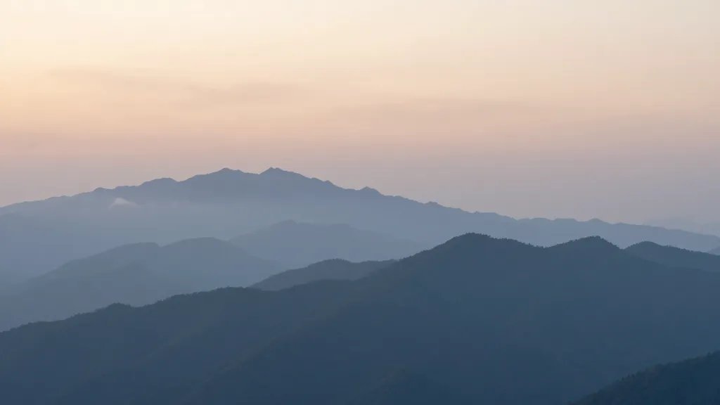 Wide mountain range horizon at dawn with soft mist over peaks