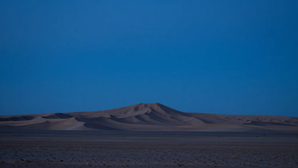 Distant desert mesa under dramatic blue-hour sky