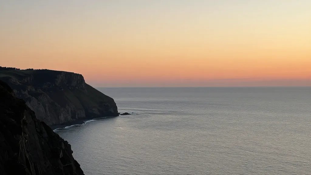 Distant view of a calm coastal cliff at sunset