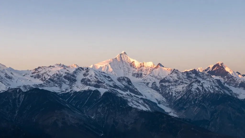 Expansive mountain range with snow-capped peaks at dawn