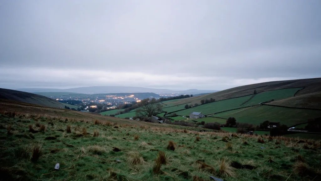 Wide hillside moor with a lone house and distant city lights horizon
