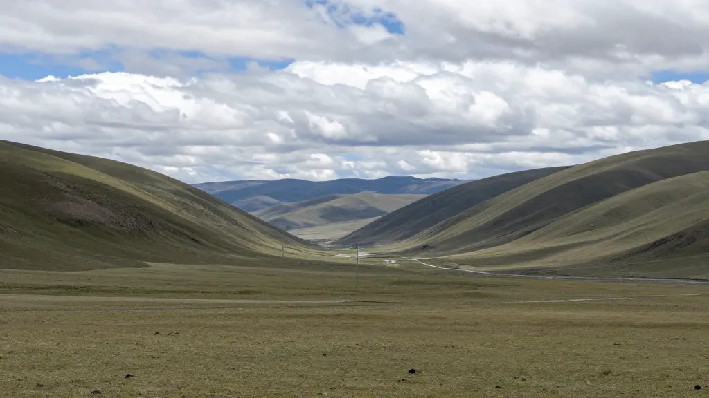 Wide-open highland valley, distant hills and clouds, tranquil financial clarity mood