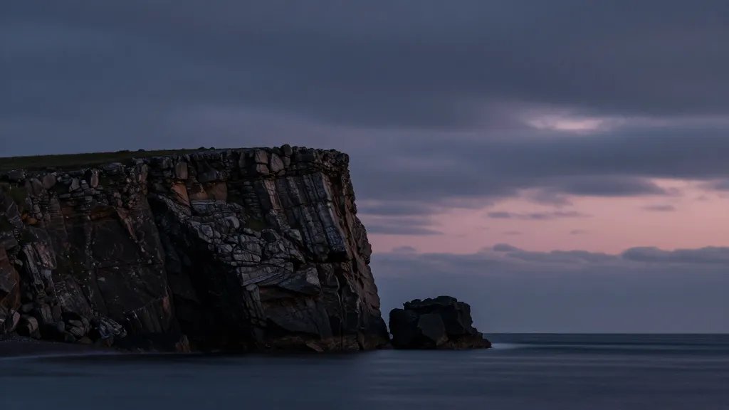 Distant coastal cliff at twilight, single rugged rock formation, dramatic sky