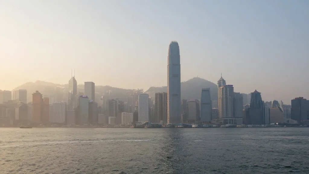 Distant view of a sunlit city skyline through a harbor mist