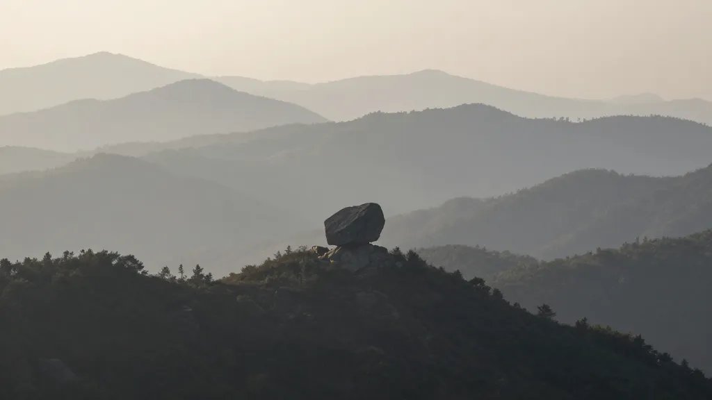 Mountain valley ridge line, solitary boulder focal point, misty morning light