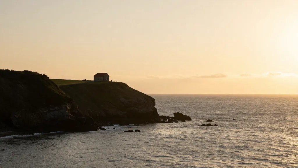 Distant coastal cliff overlooking sea, golden hour light, single house silhouette