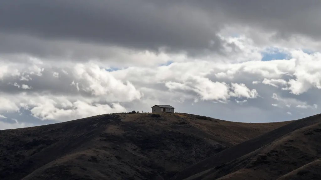 Mountain ridge beyond a single rental home with dramatic, cloudy sky