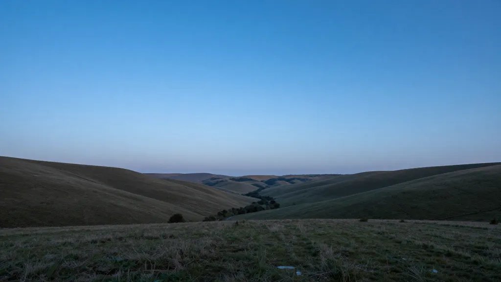 Wide valley view over rolling fields under blue hour sky