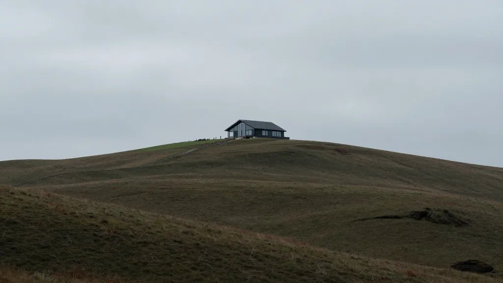Quiet valley with a distant, modern energy-efficient home on hilltop, wide landscape