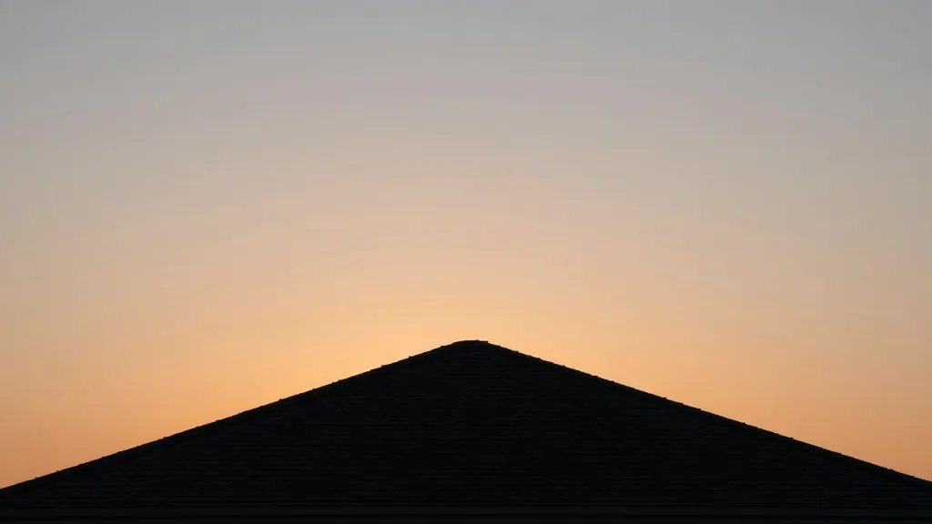 Expansive horizon with a high gabled loft roof silhouette against sunset sky