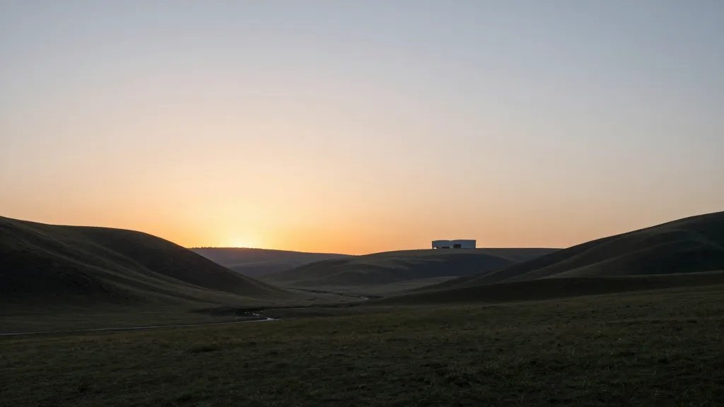 Serene valley landscape with distant sunset glow and minimalist, durable architectural silhouettes in the distance