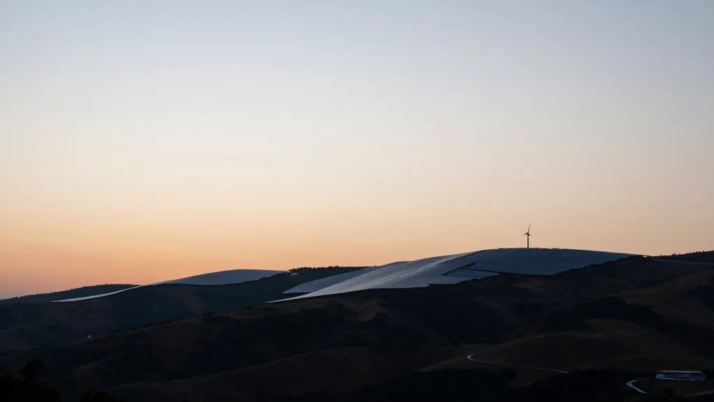 Expansive coastal valley at dusk showing a lone solar farm silhouette on far ridge