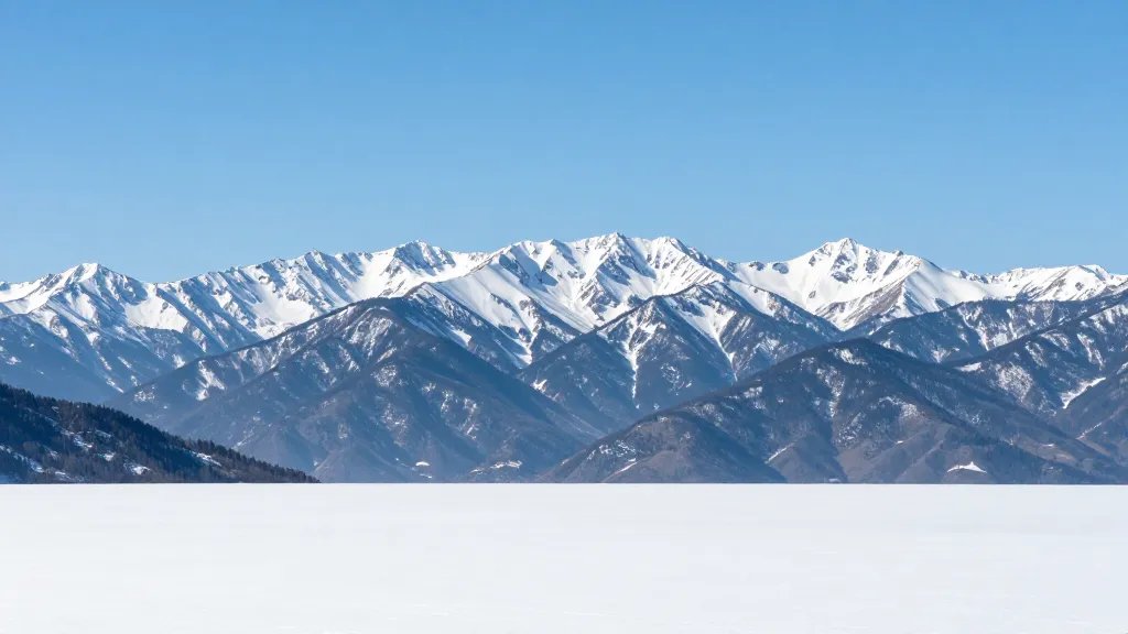 Majestic mountain range under clear blue sky, distant perspective with pristine, untouched foregroundless scene