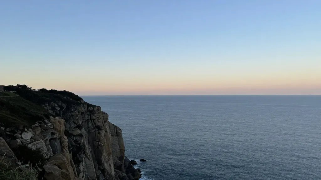 Distant coastal cliff overlooking ocean at dawn, clear horizon