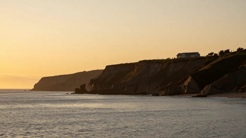 Coastal cliffline at golden hour, single property outline along shore