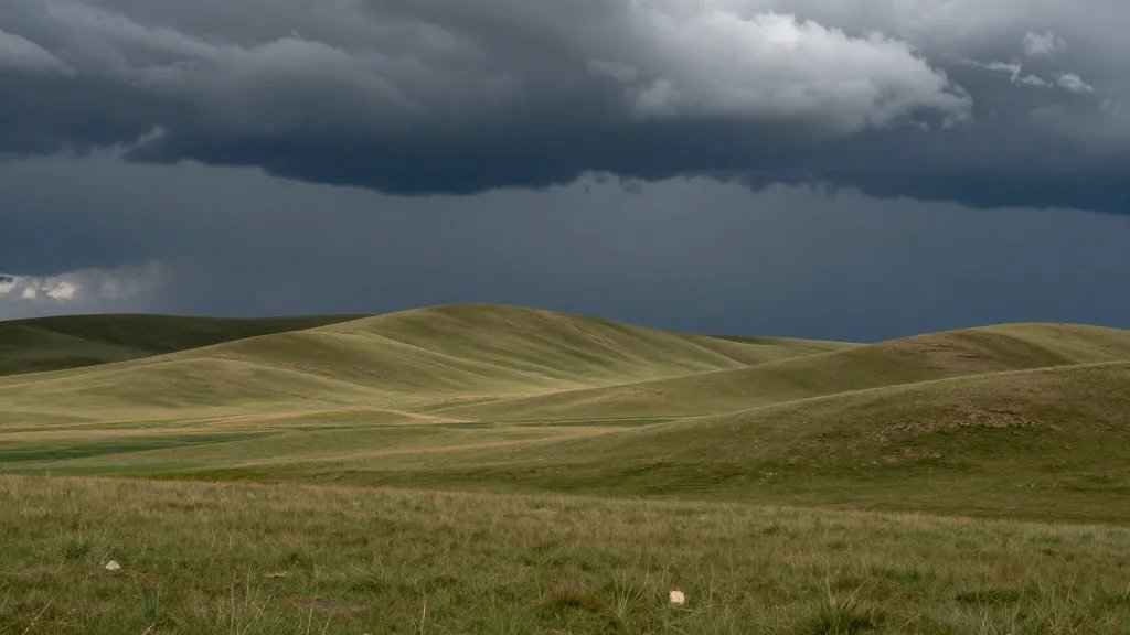 expansive prairie hillside under dramatic stormy sky, rolling fields
