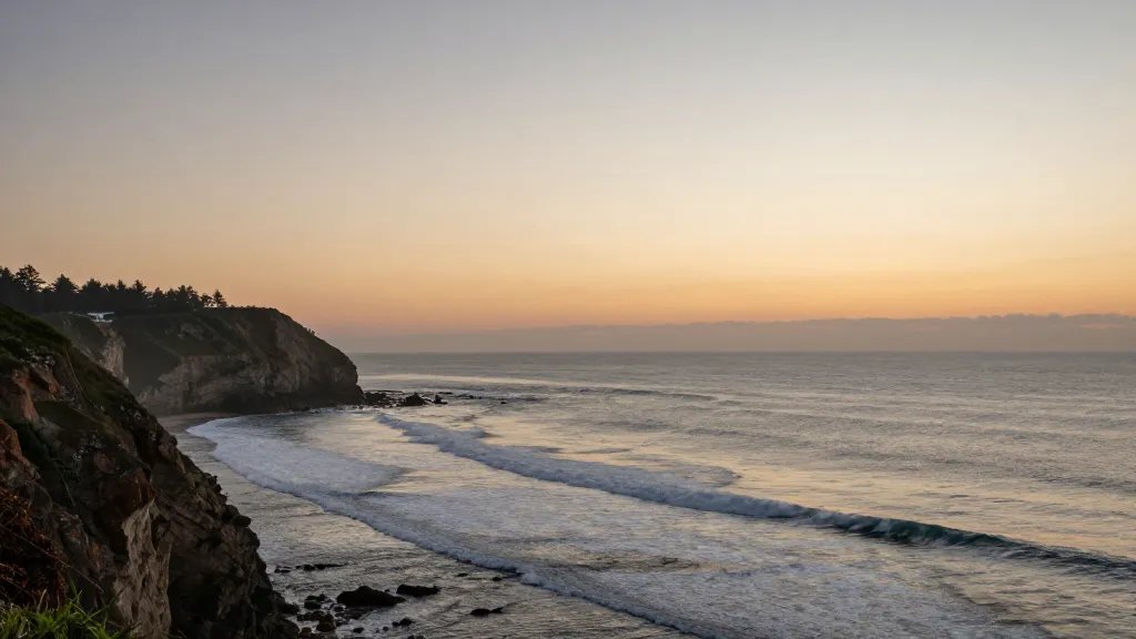 Distant view of a coastal cliff overlooking surf, sunset, calm hues