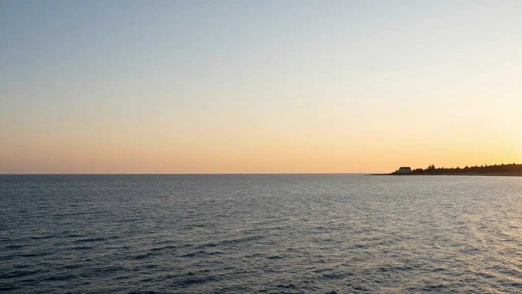 Expansive coastline view of a distant house silhouette at golden hour