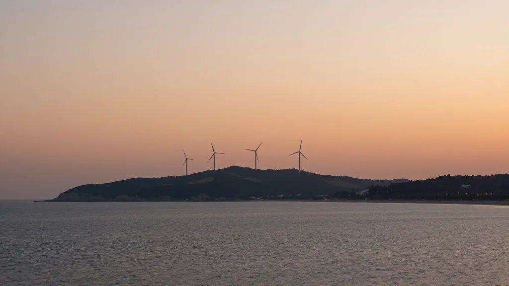 Distant hillside wind farm at sunset over calm sea